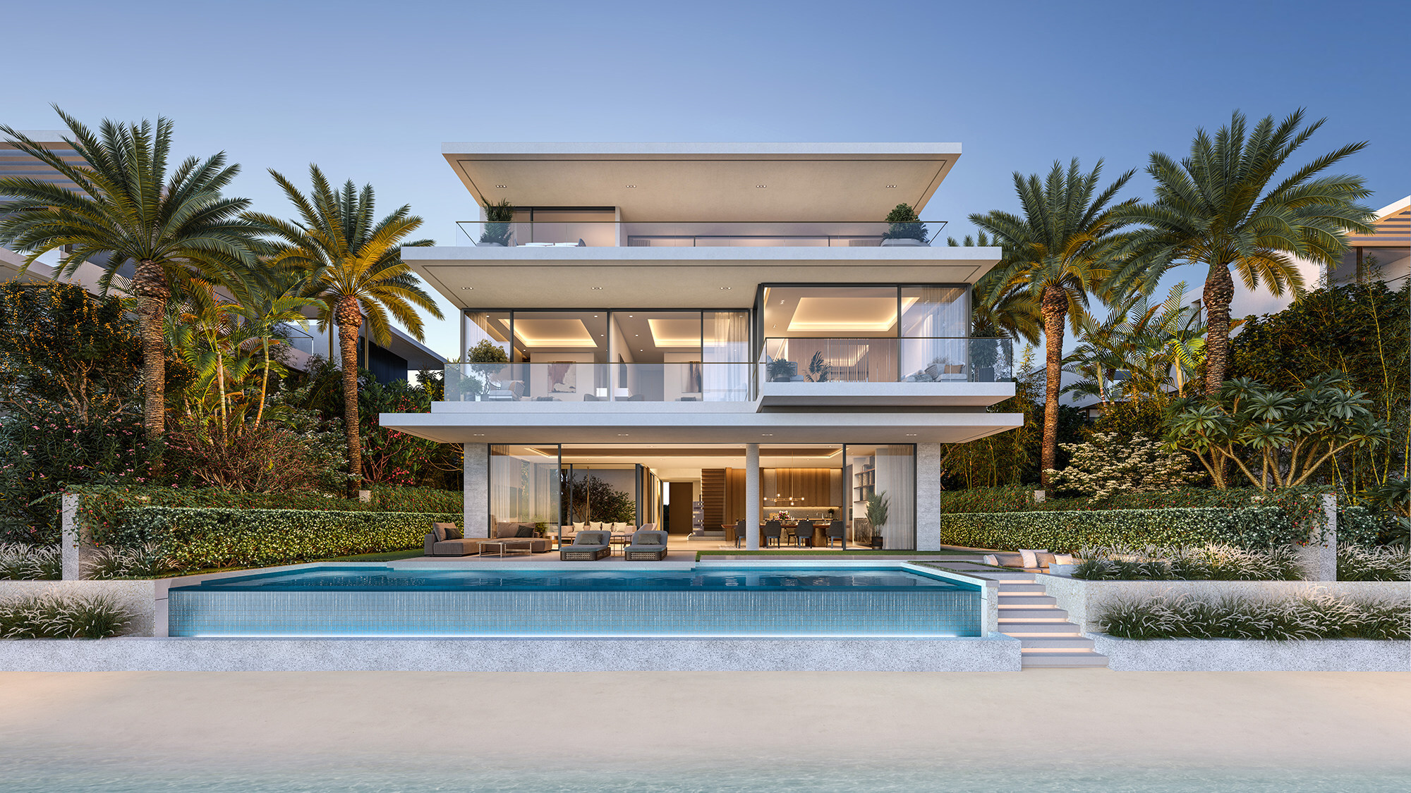 Beach Collection villa at dusk, lit from within, with its infinity pool opening directly onto the sand